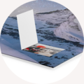 Åpen CEWE fotobok på blå bakgrunn, med et synlig bilde.