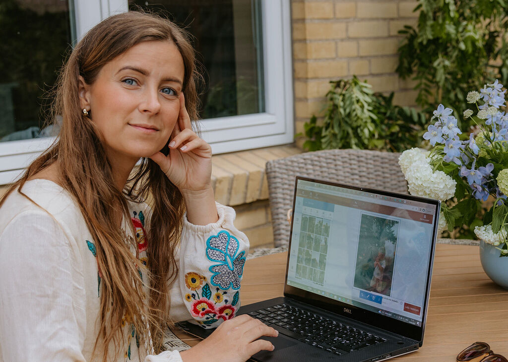 En person arbeider på en laptop ute med blomster i en avslappet atmosfære.