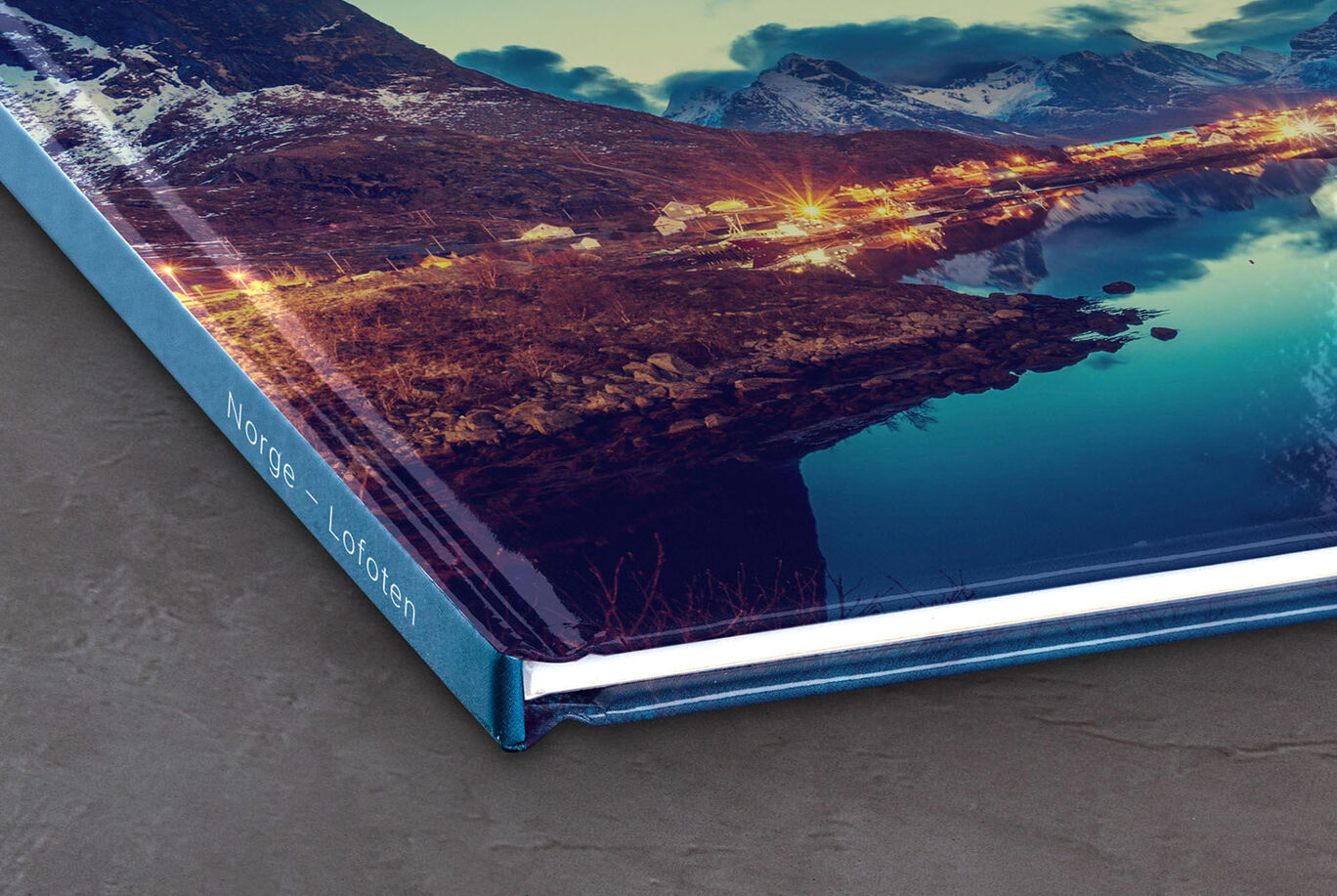 Detaljert visning av et CEWE FOTOBOK som viser vakker landskap. Det glansfulle omslaget viser solnedgangens farger.